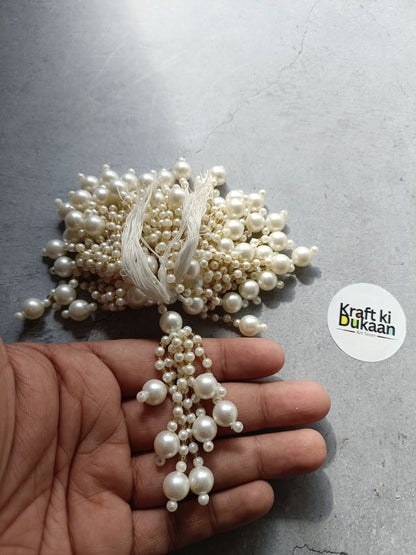 Pearl beaded tassel latkan with multiple dangling strands on a hand-held display