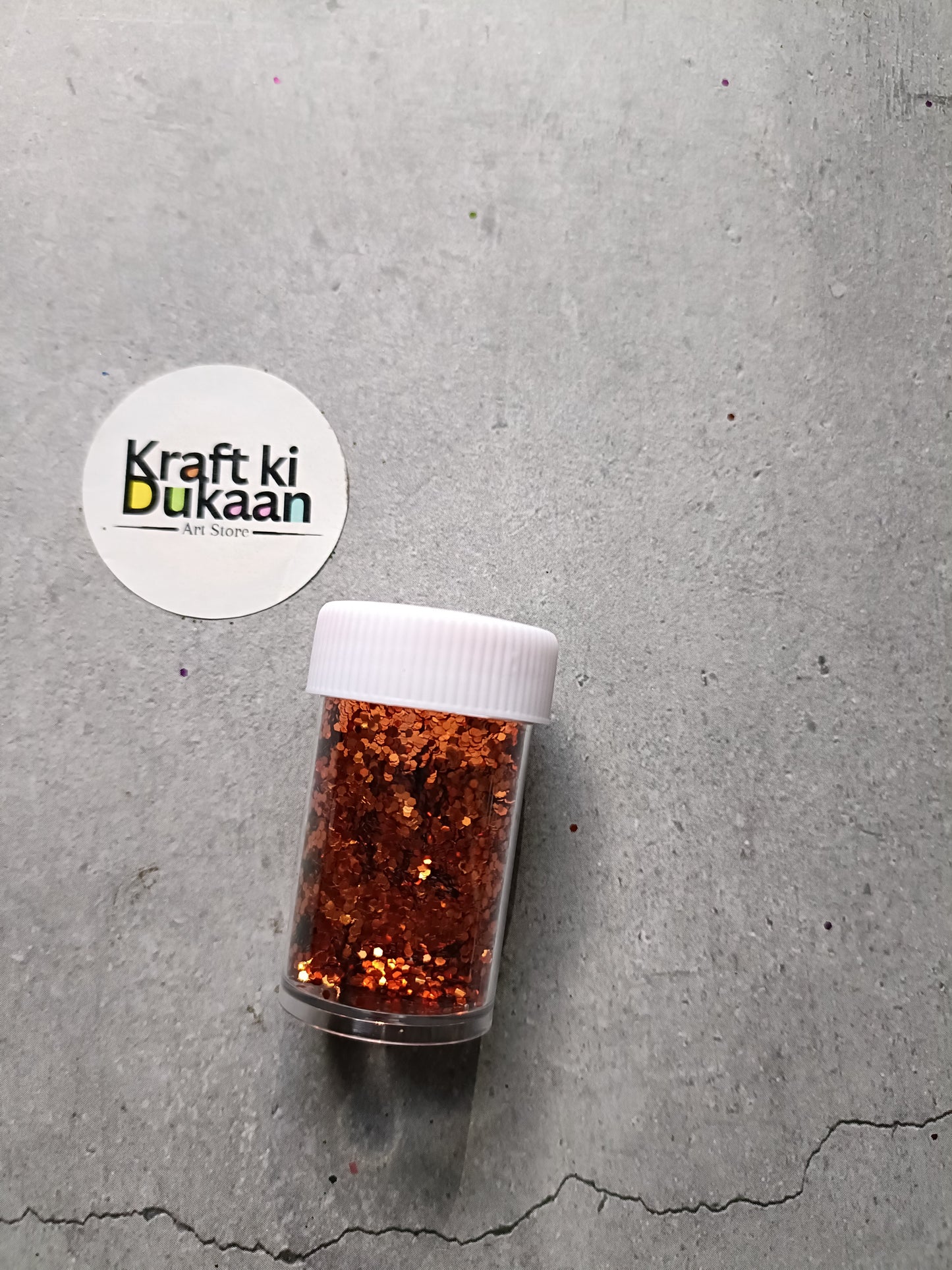 Hexagon glitter jar with copper-brown glitter in a small white-lidded bottle