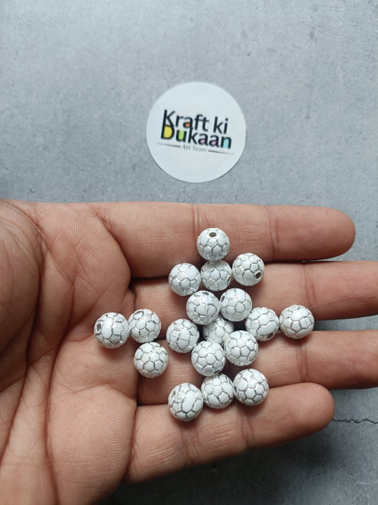 Rakhi bracelet beads: round white soccer-ball patterned beads in hand