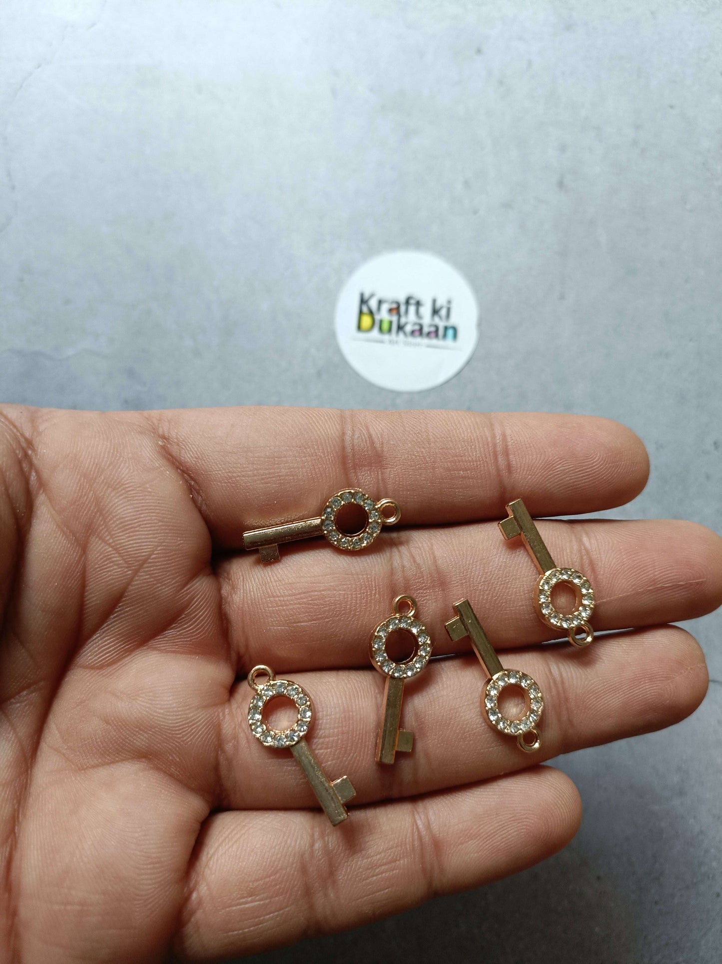 Gold-tone rhinestone key pendant charms set in hand, round crystal ring details