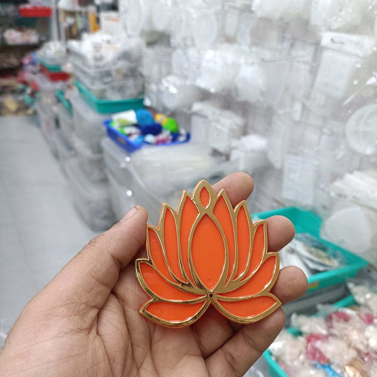 Orange lotus acrylic tea light holder with gold trim, shown in hand