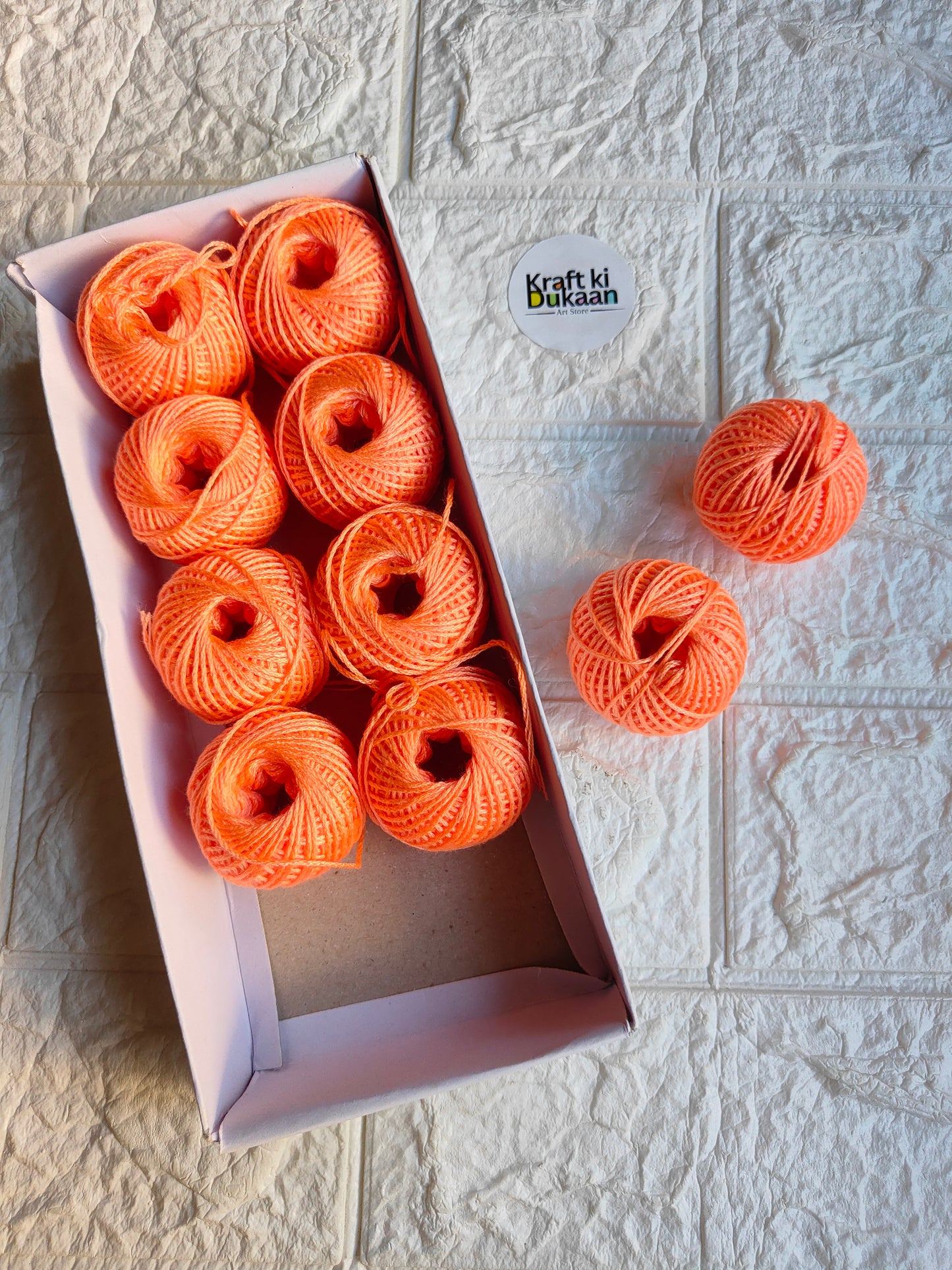 Rakhi thread roll set with orange yarn balls in an open cardboard box