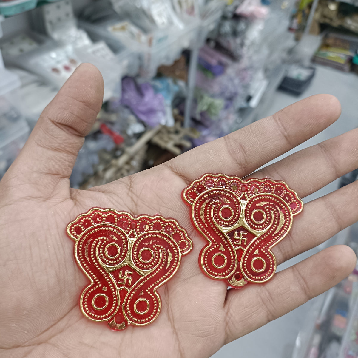 Red heart-shaped acrylic charan embellishments with gold and white trim, pair on hand