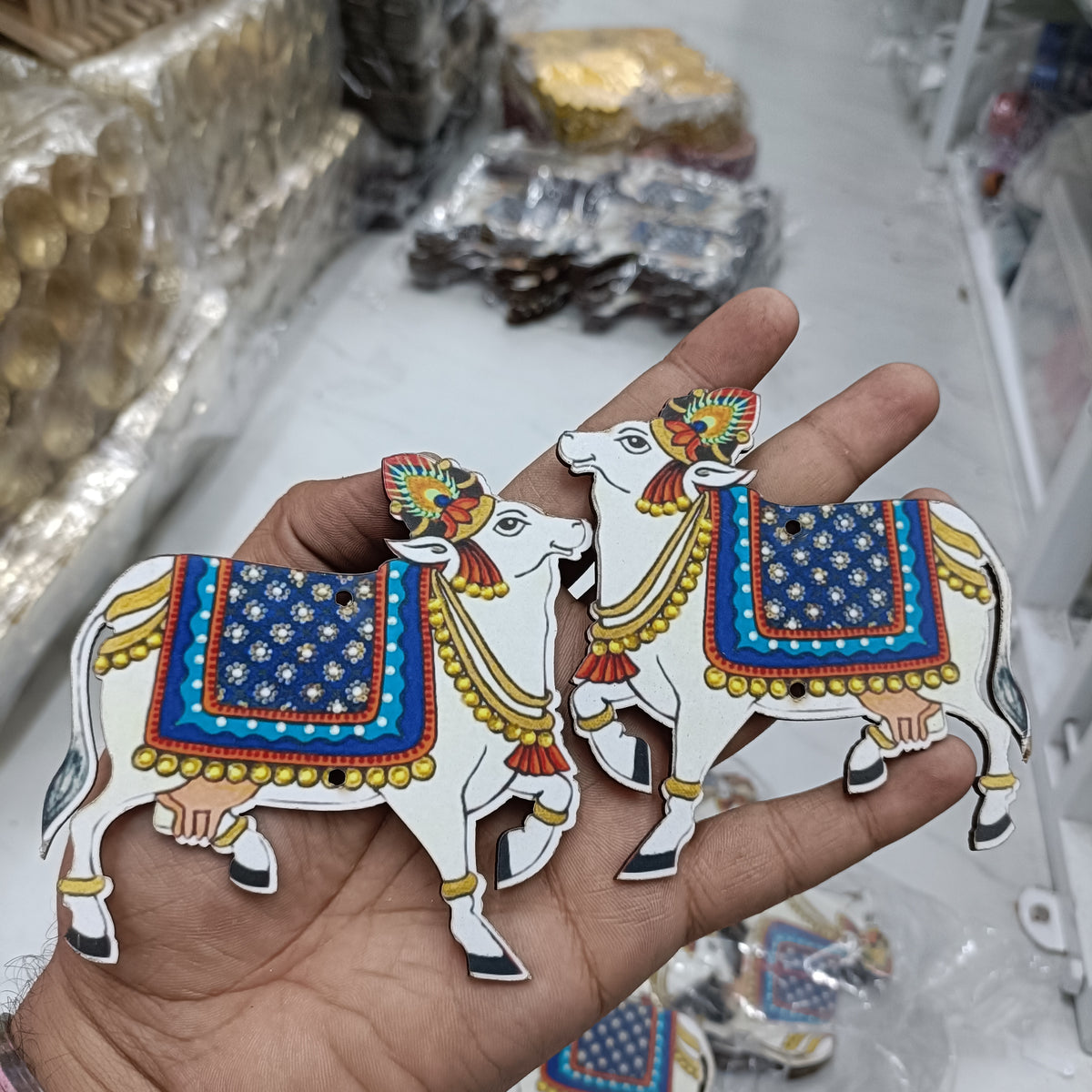 Blue-and-gold cow cutout pair, shaped MDF set held in a hand