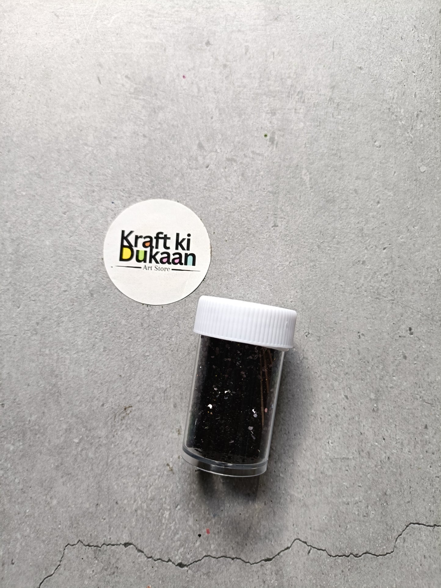 Hexagon glitter jar with black glitter in a small white-lidded bottle