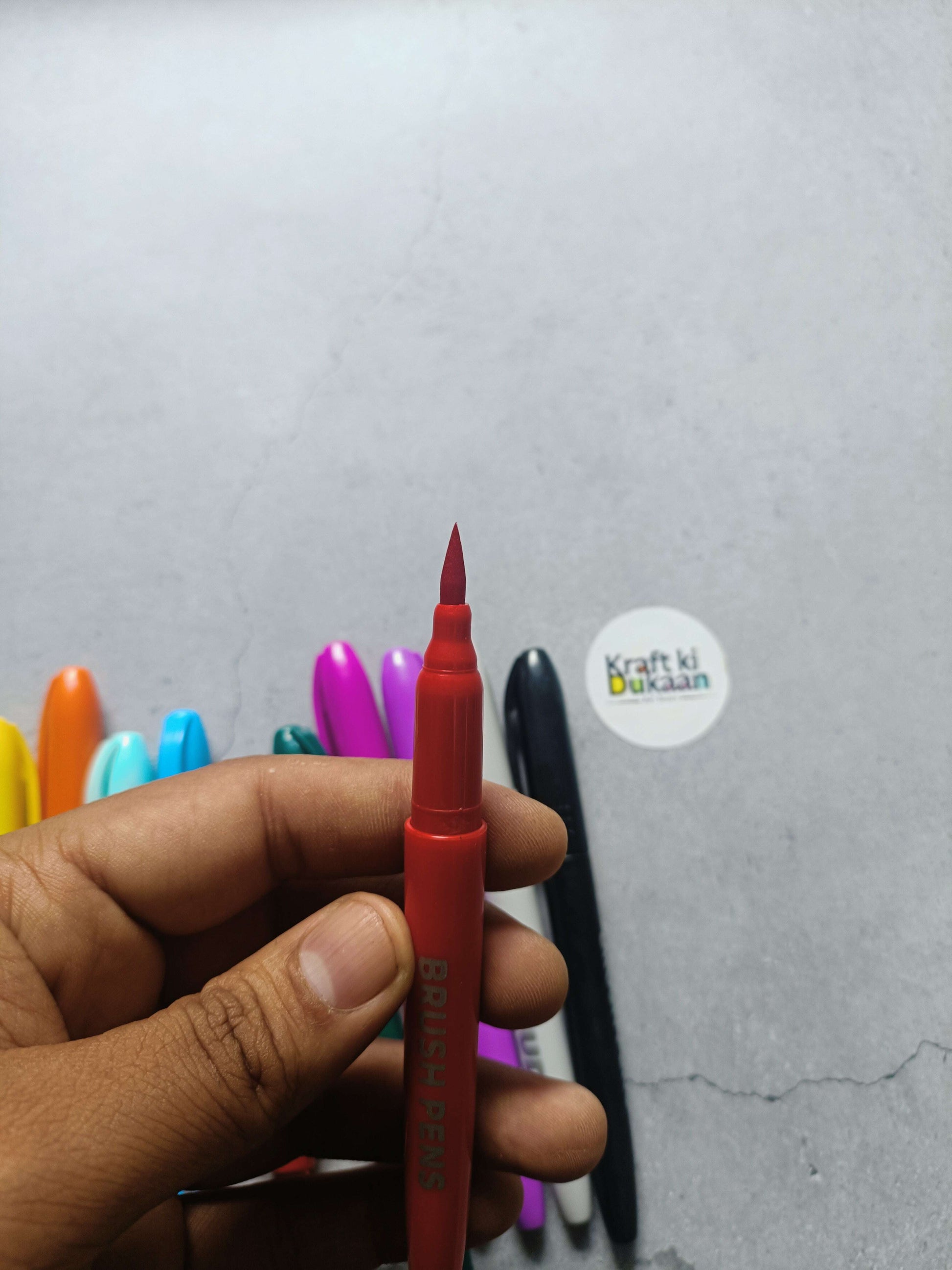 Red brush pen with angled tip, held in a hand