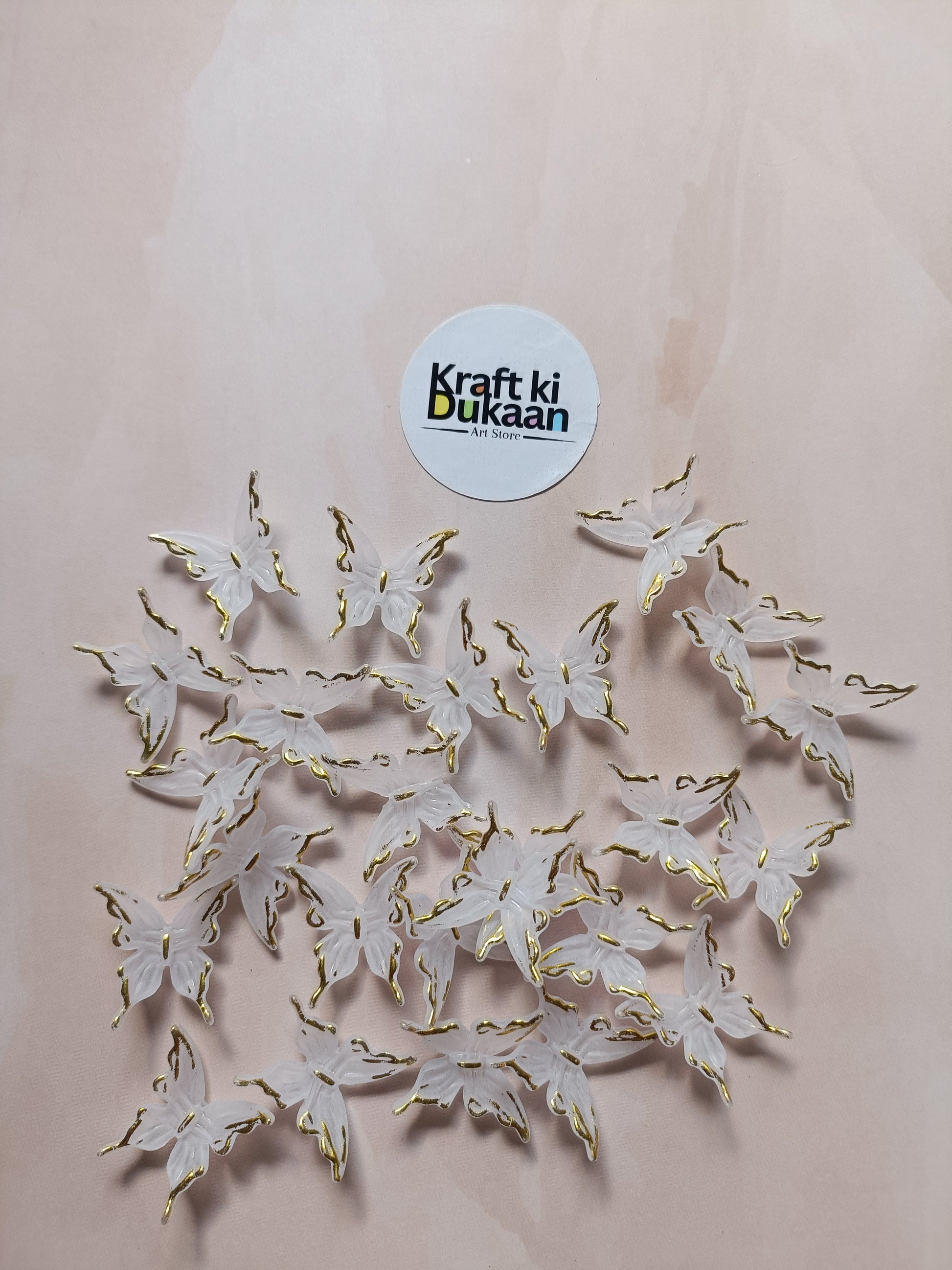 Butterfly bead pack of 25, gold-tone and white butterfly charms laid out