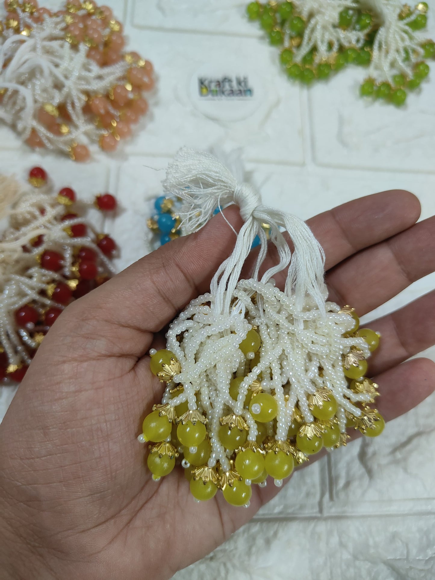 Beaded tassel with white fringe, green and gold dangling beads