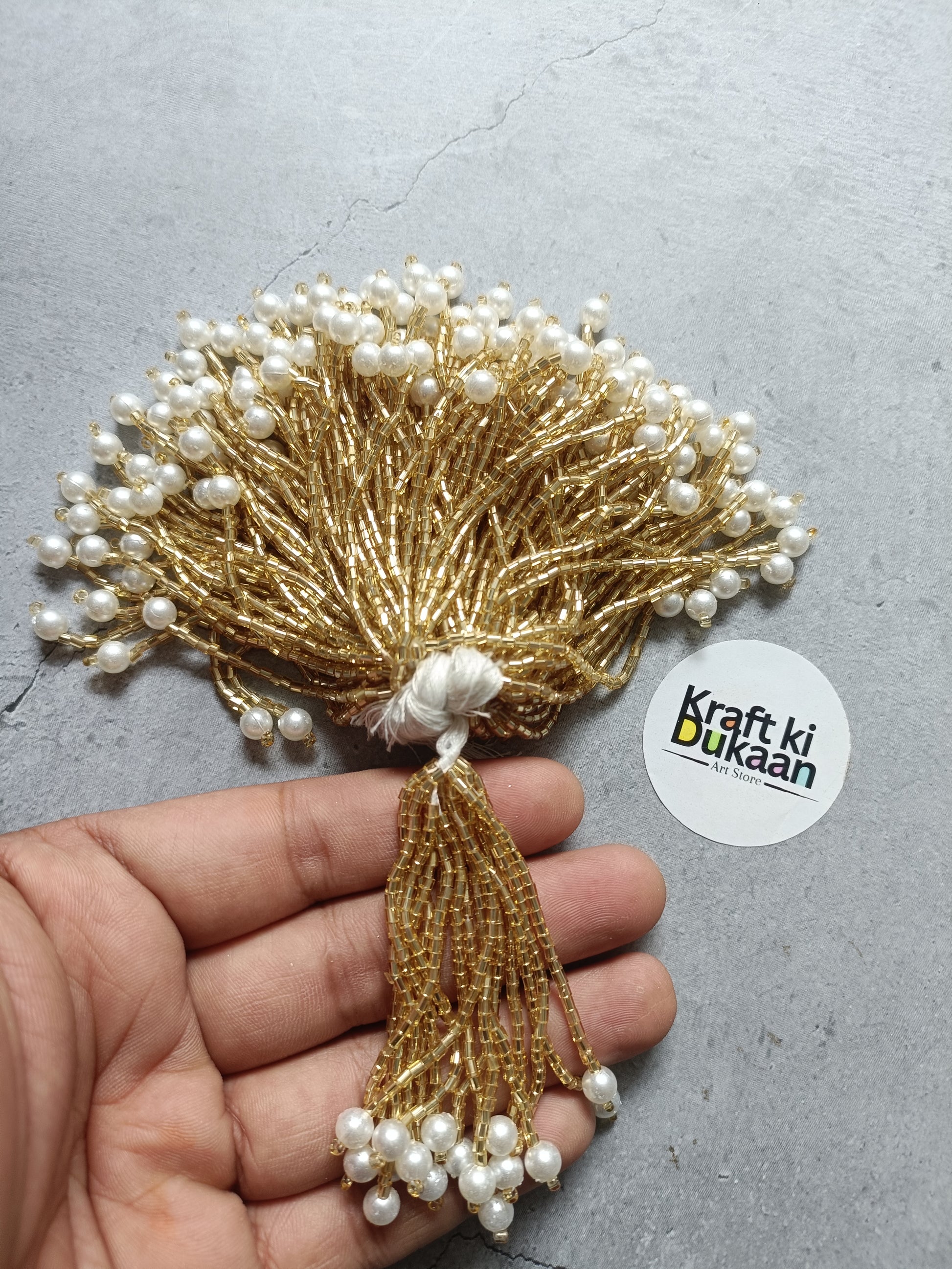 Gold pearl tassel embellishment with white bead fringe and wire bundle