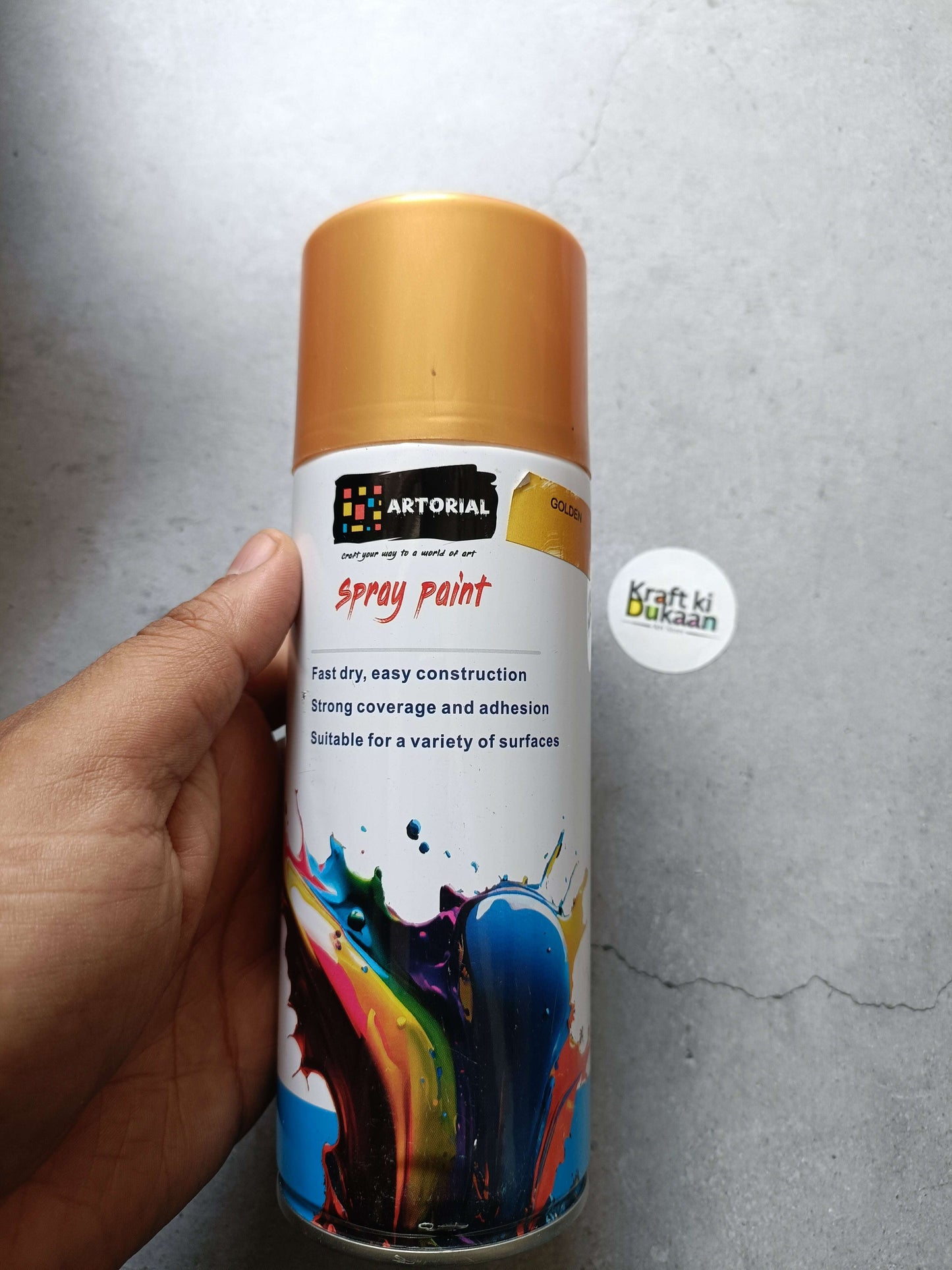 Golden spray paint can with colorful splatter artwork and “Kraft ki Dukaan” sticker