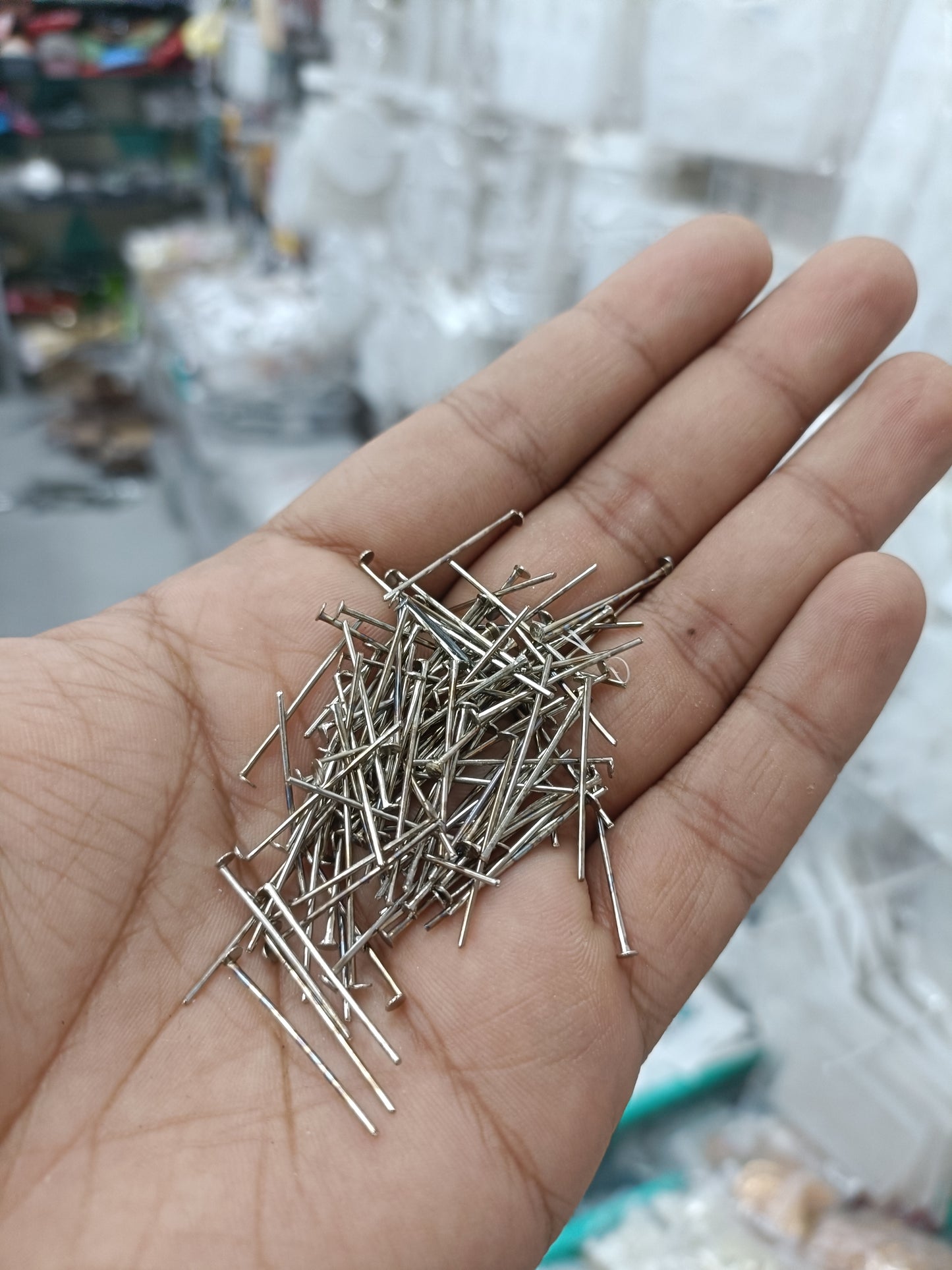 Silver jewellery head hook pins with visible metal heads in palm