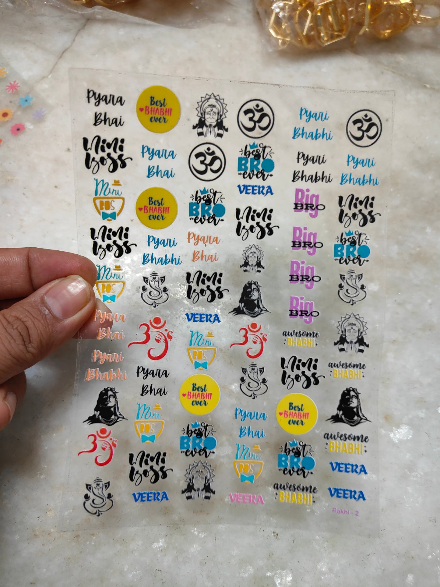 Peel-off sticker sheet with colorful Om symbols, text, icons, and small character graphics