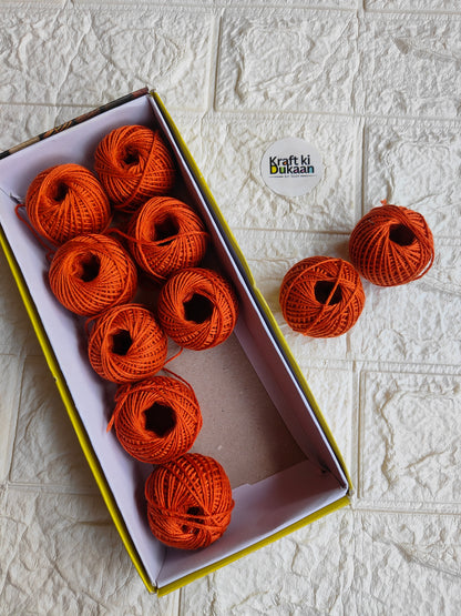 Rakhi thread roll with orange-red thread balls in open cardboard box