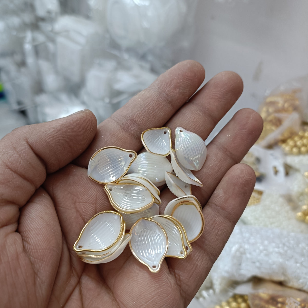 Gold-trim white acrylic petal beads in hand, 50-pack, leaf-teardrop shape