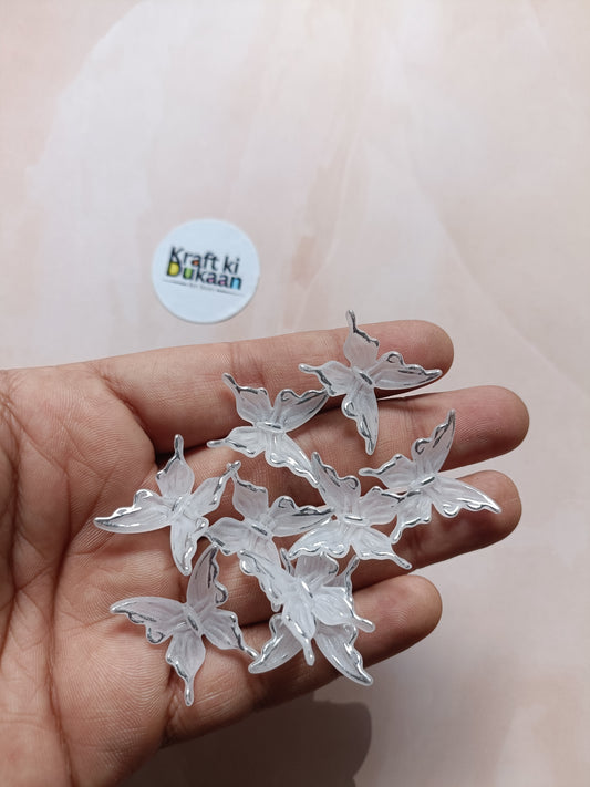 Silver butterfly beads with hanging loops, held in hand