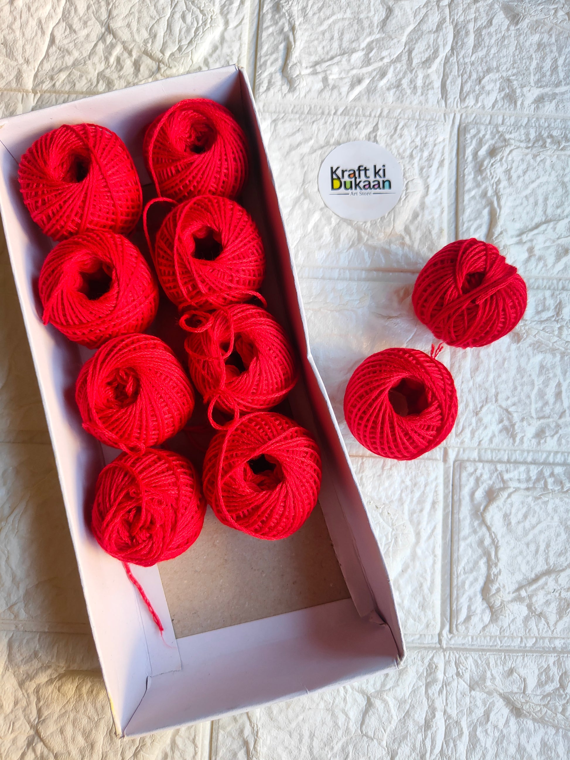 Rakhi thread roll set with bright red yarn balls in an open cardboard box