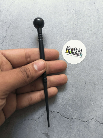 Black clay modelling ball-end tool with slim rod, held in hand