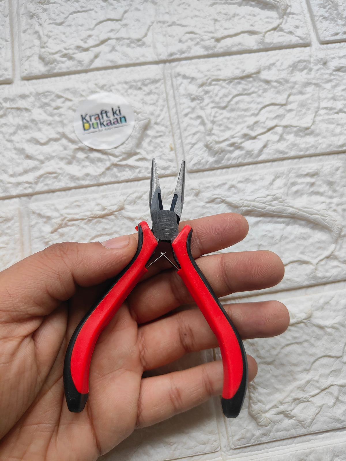 Red and black needle-nose pliers with insulated grips and pointed jaws
