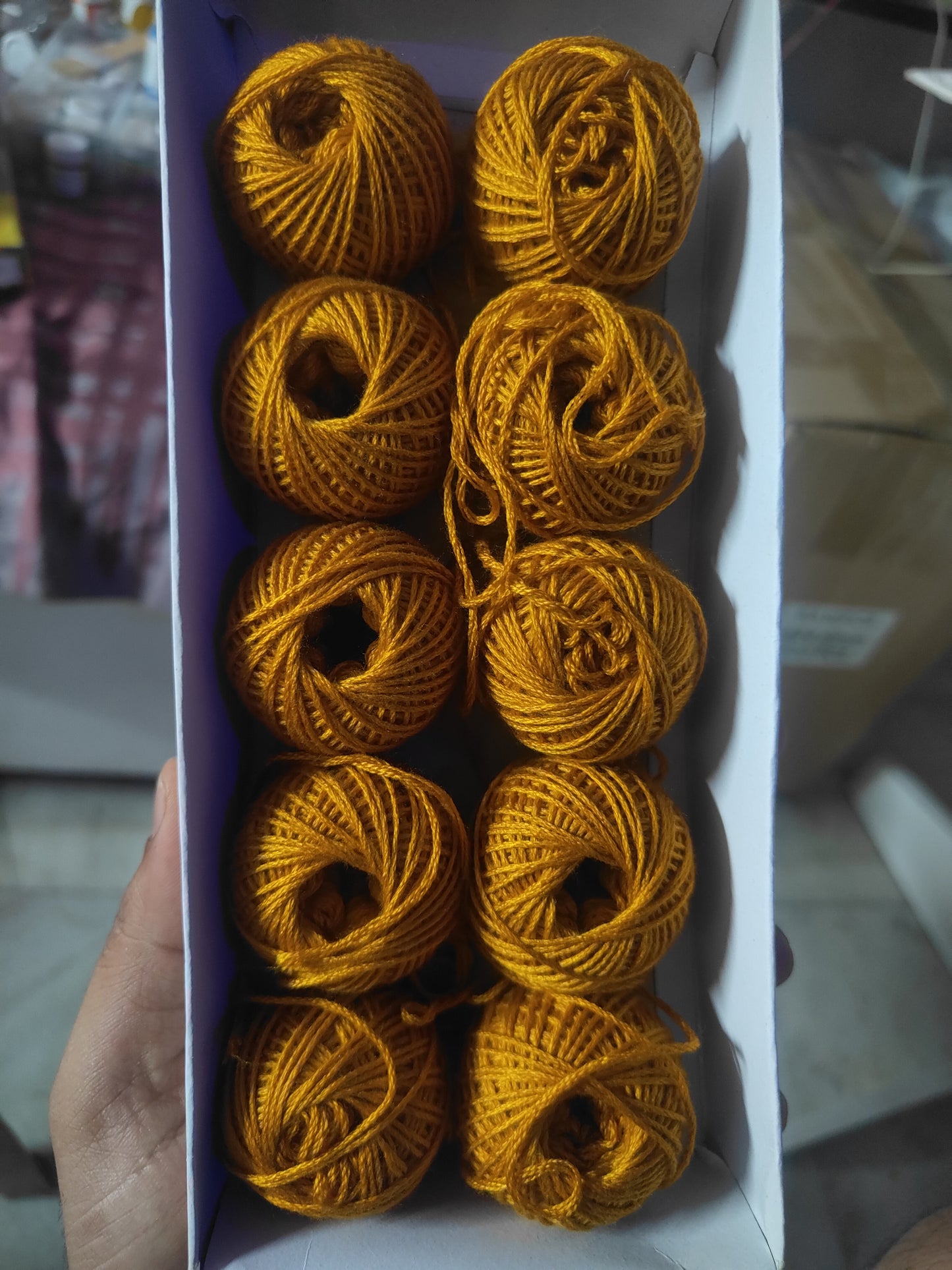 Rakhi thread roll set with golden yellow yarn balls in an open cardboard box