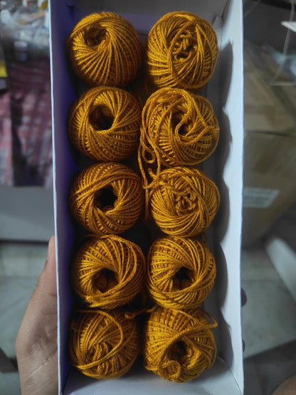 Rakhi thread roll set with golden yellow yarn balls in an open cardboard box