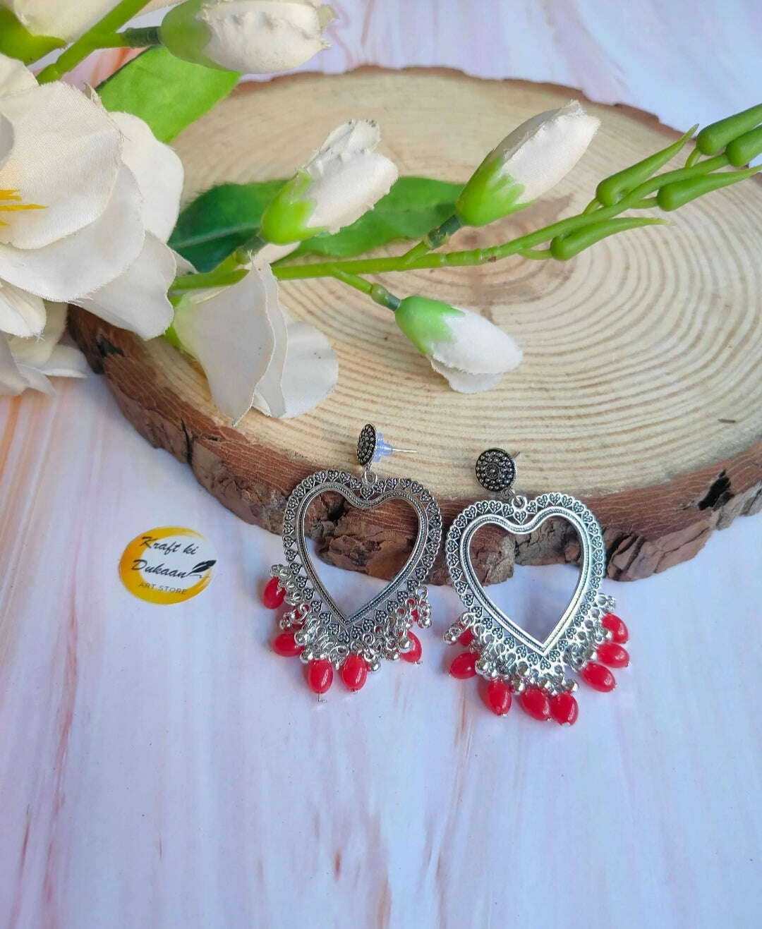 Silver heart-shaped jhumka earrings with red beads, ornate heart frame
