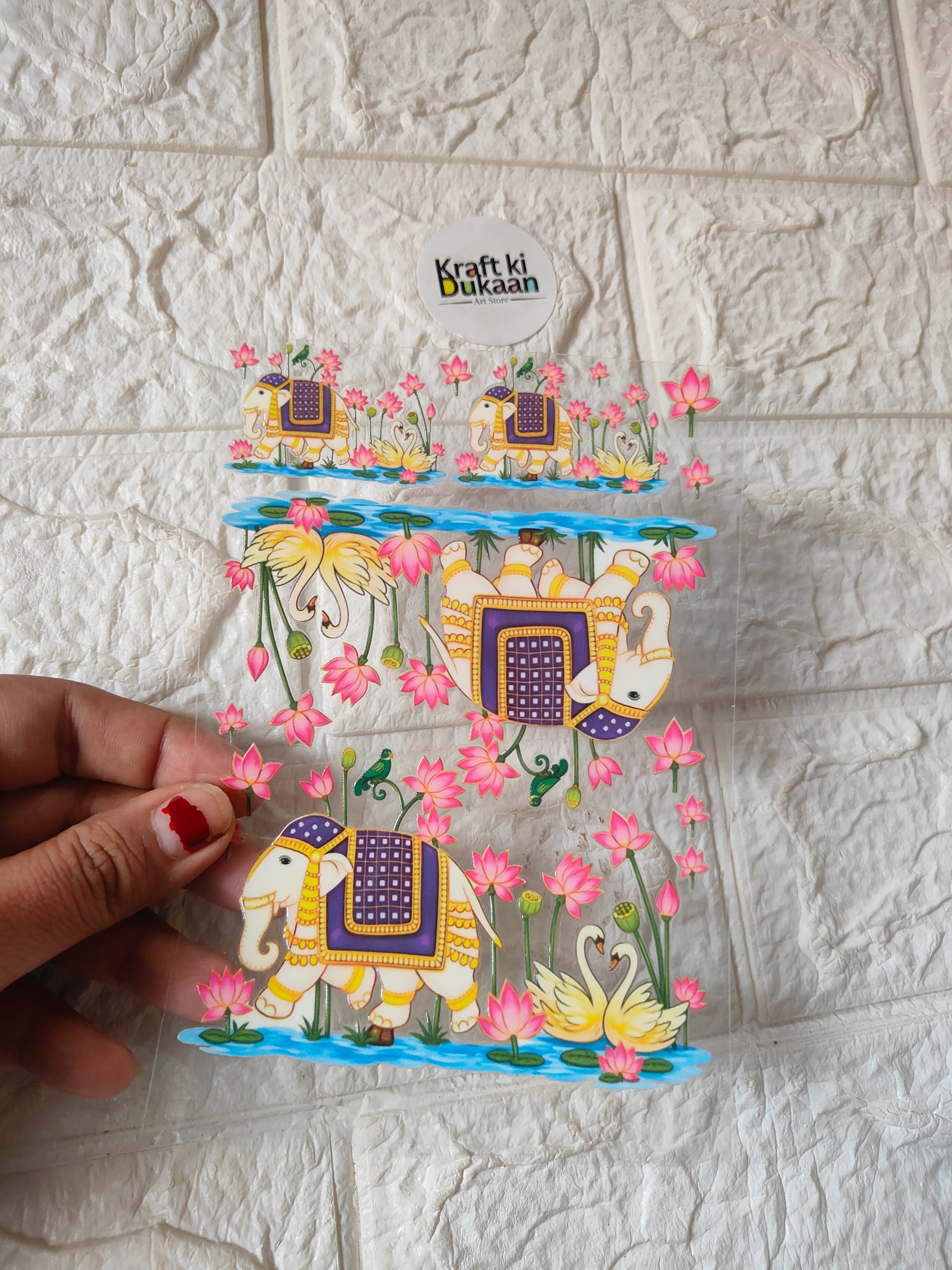 Peel-off sticker sheet with colorful camel, florals, and lantern designs, held by hand