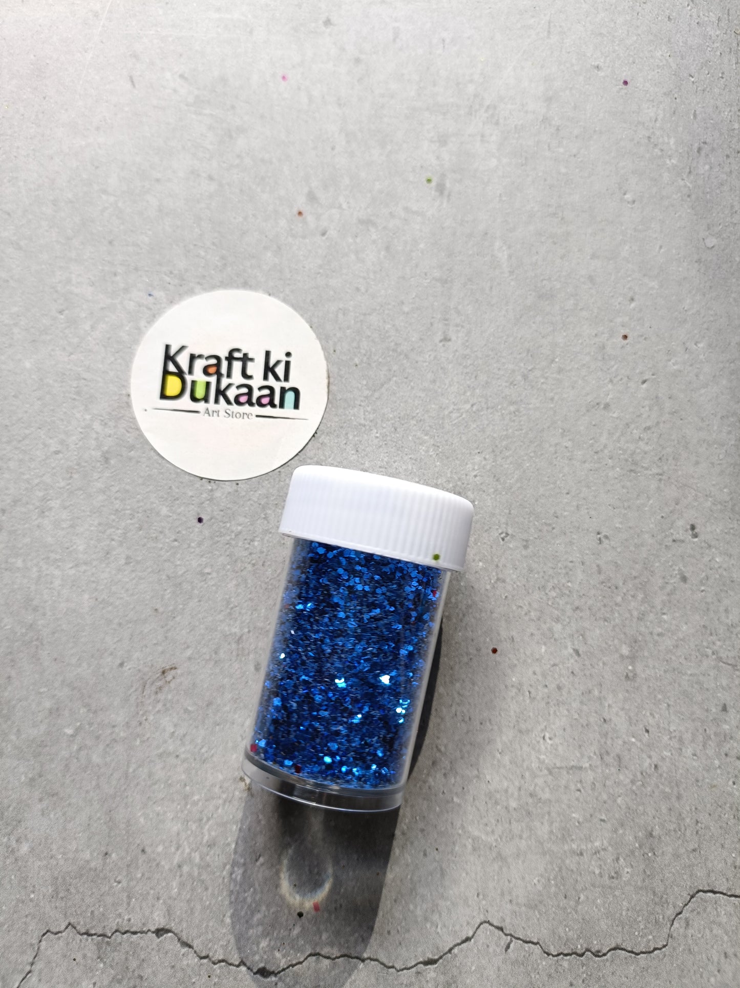 Hexagon glitter jar with royal-blue glitter in a small white-lidded bottle