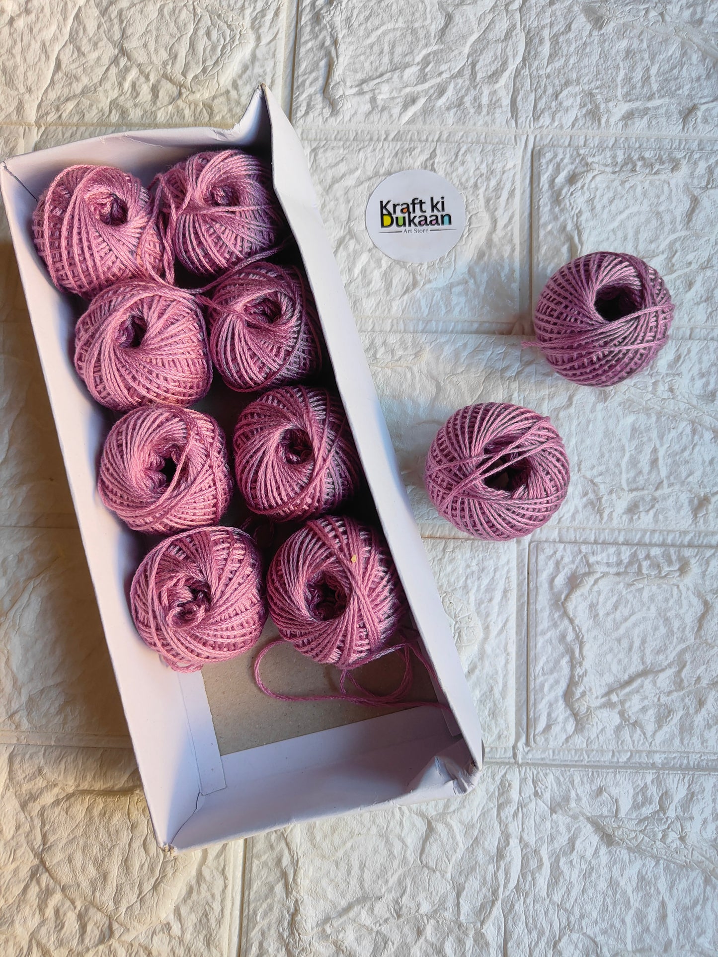 Rakhi thread roll with pink yarn balls in an open box and one loose ball
