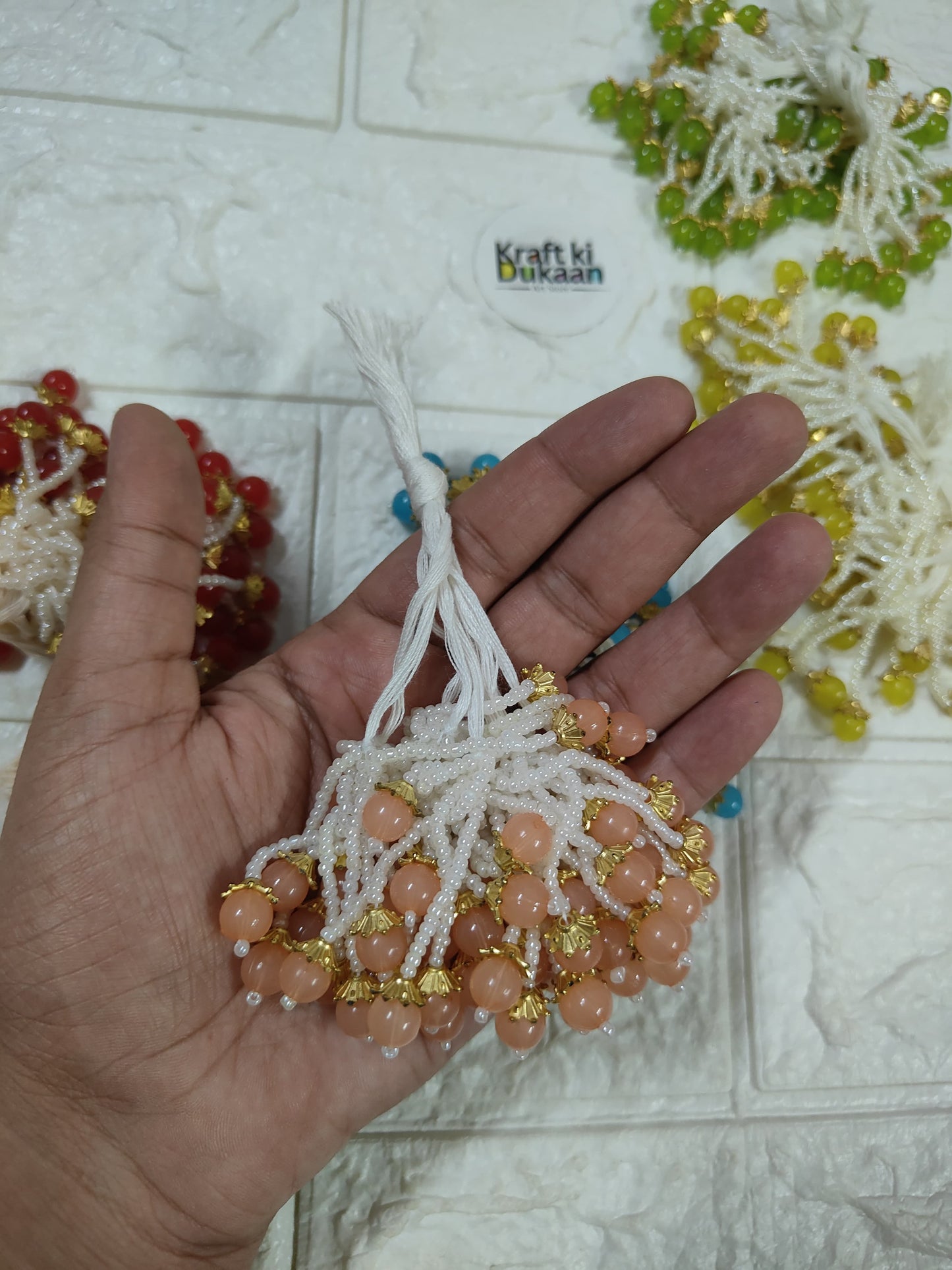Beaded tassel with white fringe, pink peach beads and gold accents