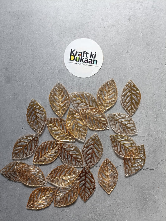 Gold leaf-shaped bead charms laid out, multiple pieces