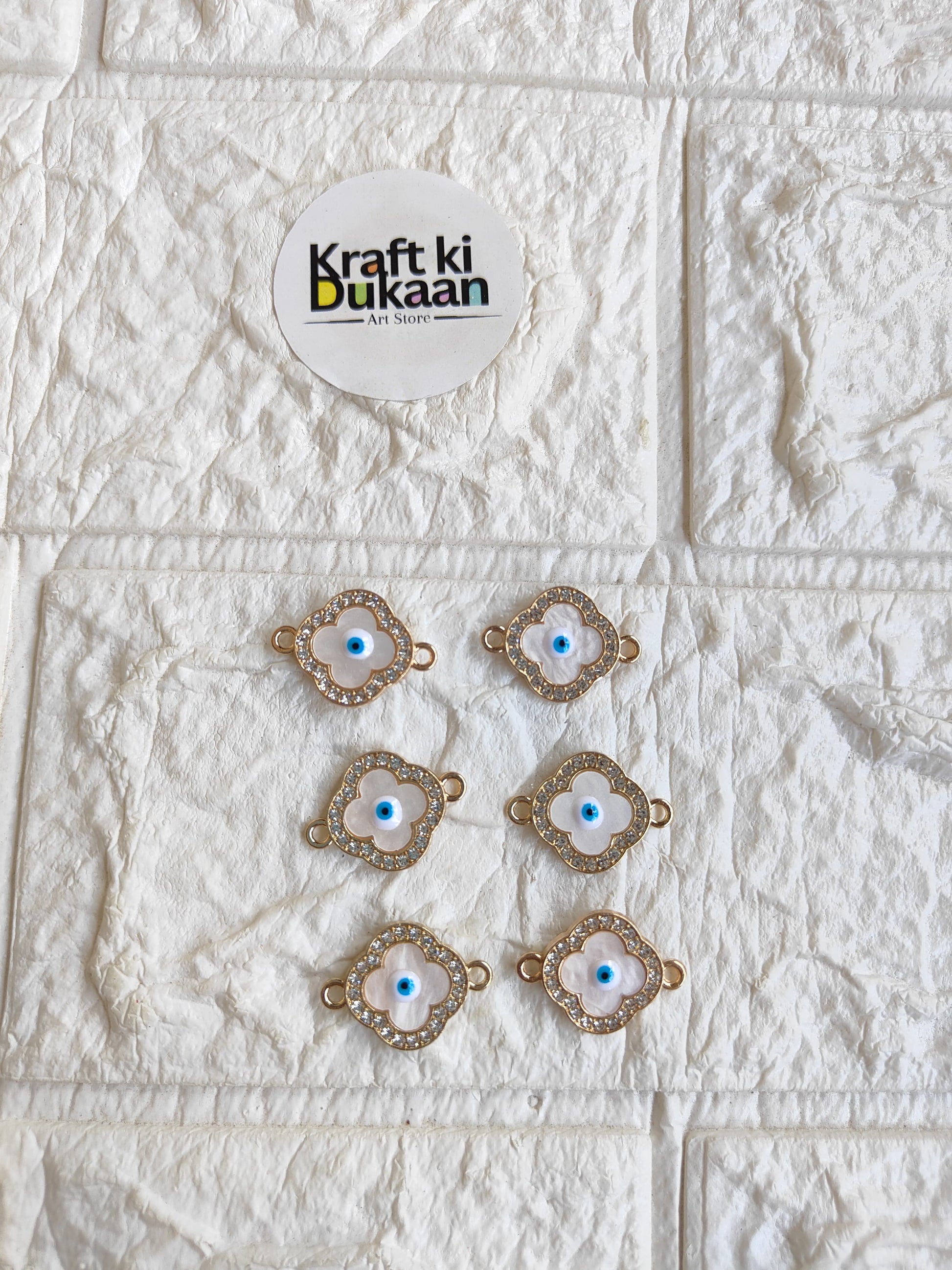 Gold-tone rakhi bracelet pendant set with blue evil-eye motifs, arranged on surface