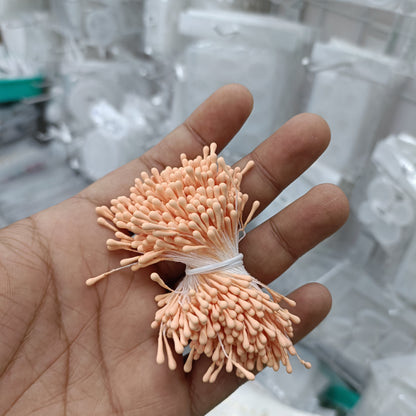 Artificial pollen bunch with pale peach bristle flowers tied with white string