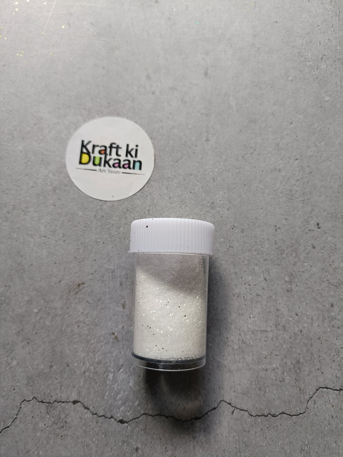 White chunky glitter powder jar with white lid.