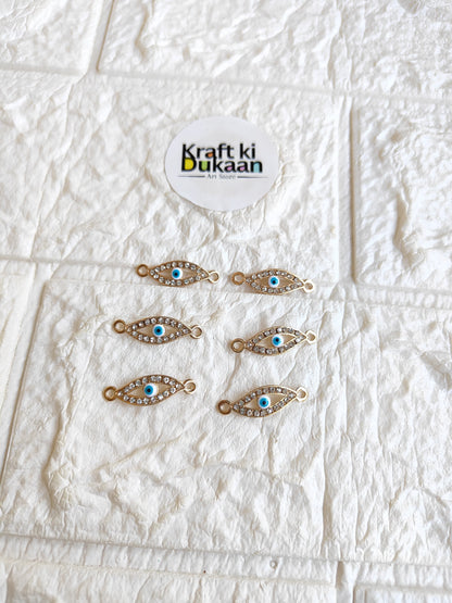 Pack of 5 gold-tone rakhi bracelet pendants with blue oval eye motifs, laid out