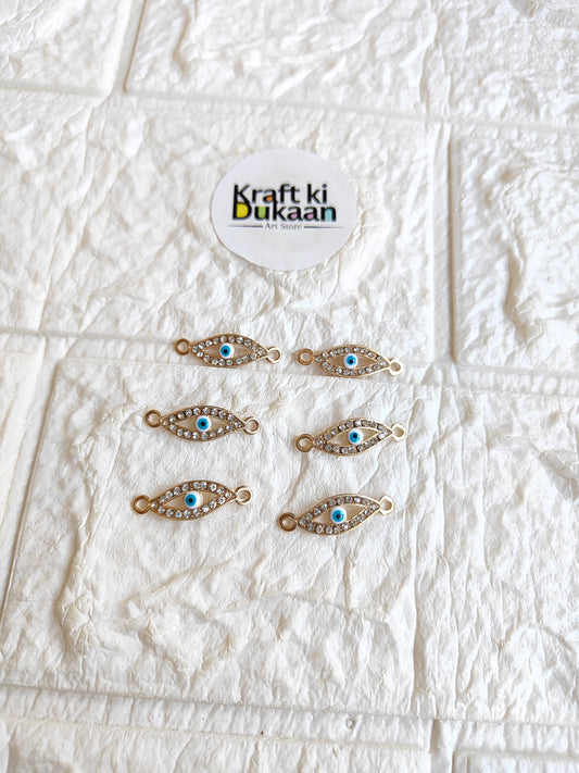Pack of 5 gold-tone rakhi bracelet pendants with blue oval eye motifs, laid out