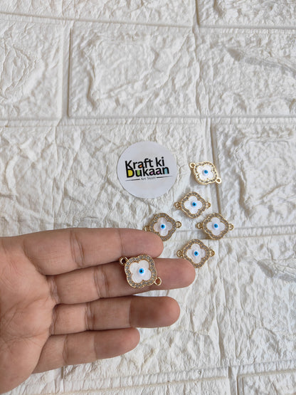 Gold-tone rakhi bracelet pendants with blue evil-eye motifs, held in hand