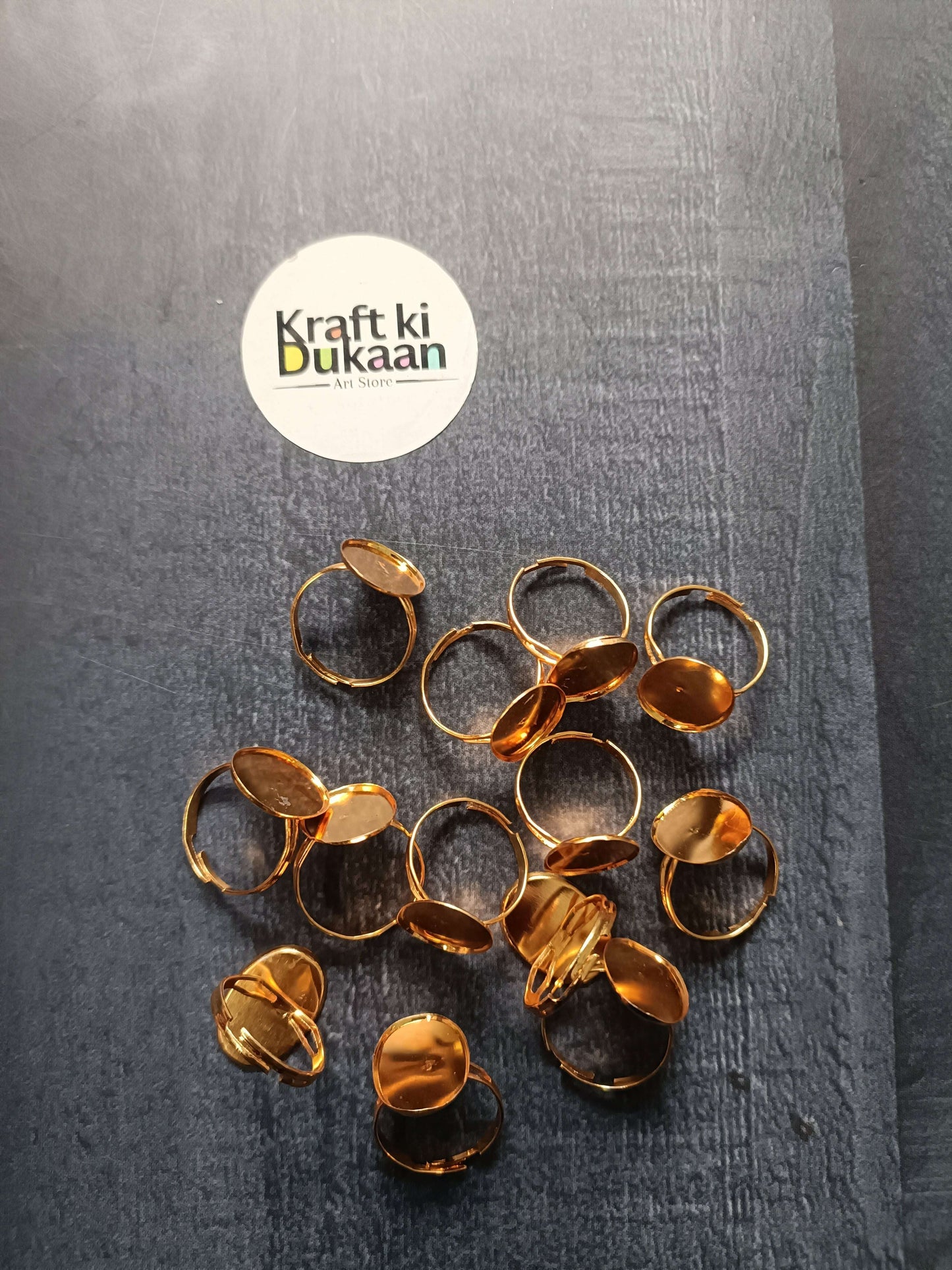 Gold-tone ring bases laid out, mixed round, oval, and square bezel open bands