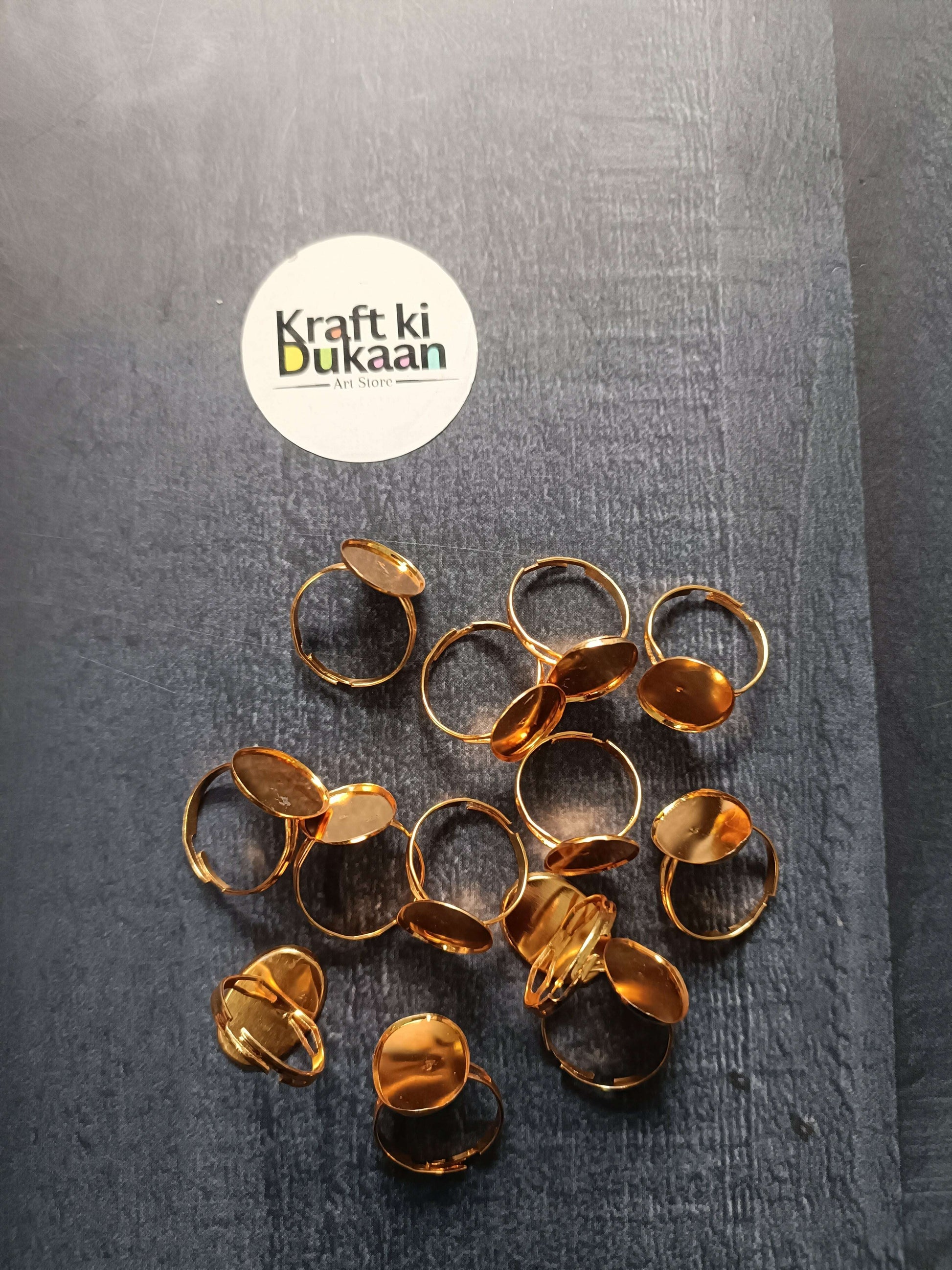 Gold-tone ring bases laid out, mixed round, oval, and square bezel open bands