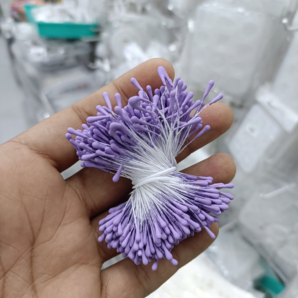 Artificial pollen bunch with lavender-purple bristle flowers tied with white string