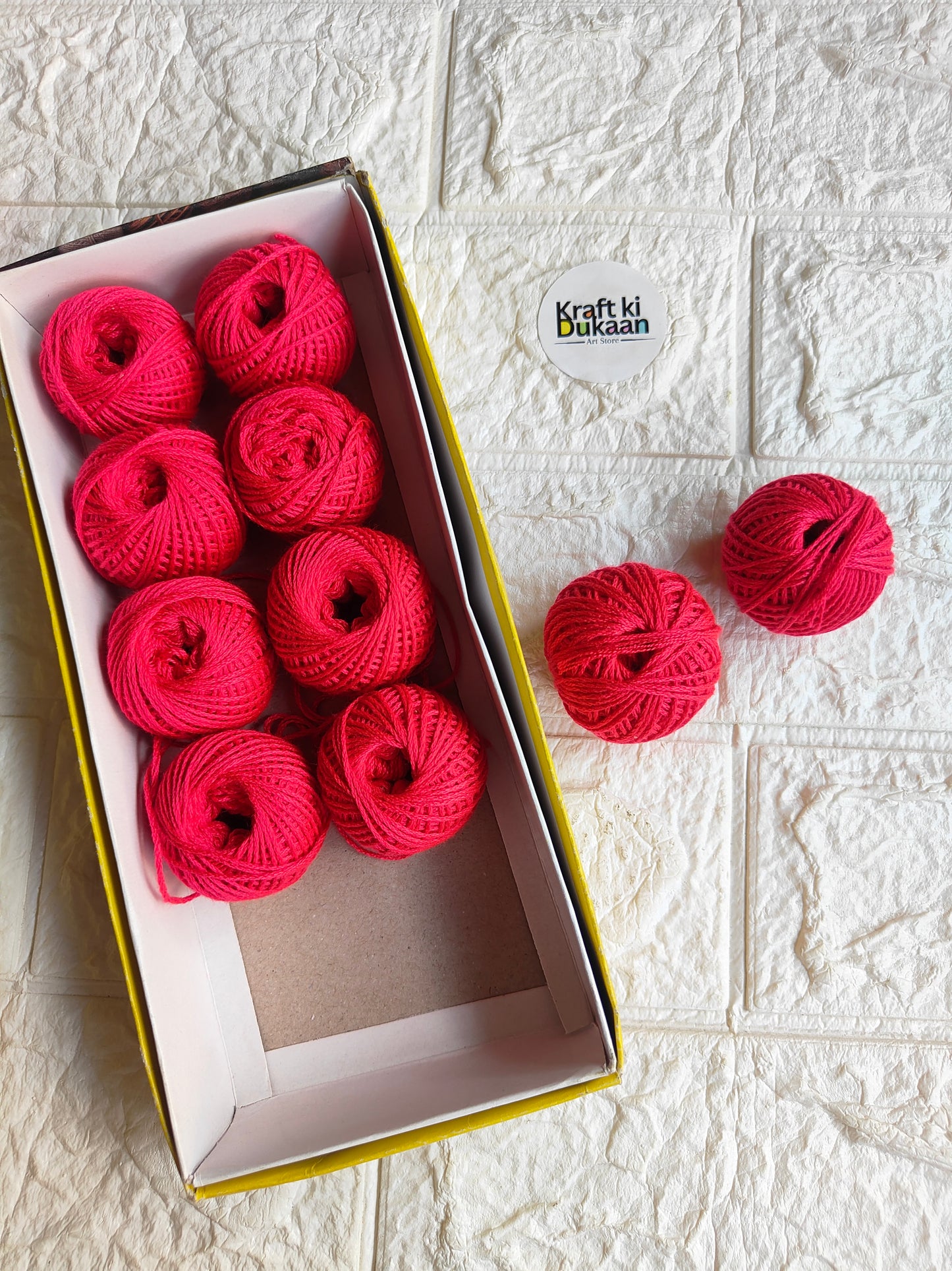 Rakhi thread spool set in vibrant pink-red, open box with several thread balls