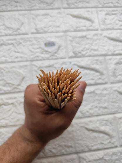 Bundle of wooden bamboo chopsticks held in hand, rounded tips visible