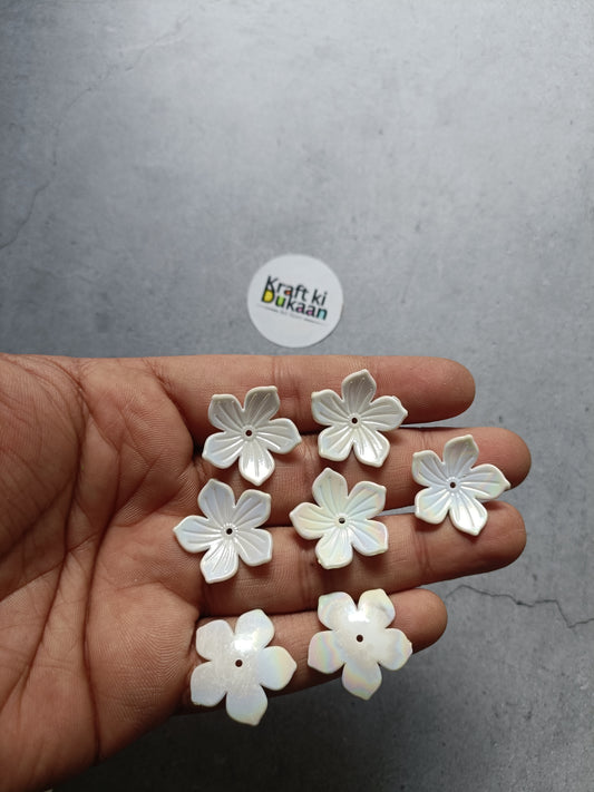 White flower-shaped beads, five-petal design, held in hand