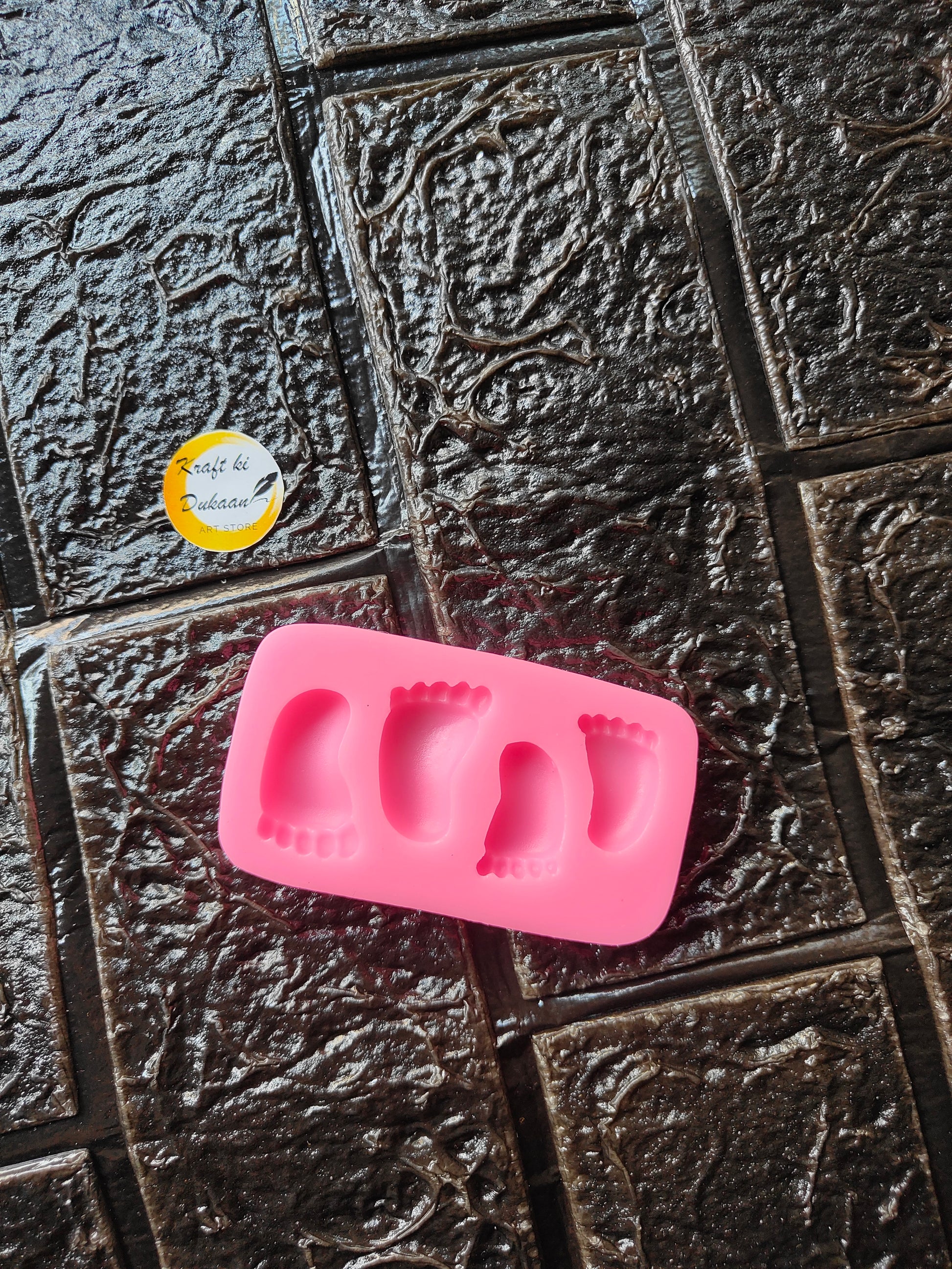 Pink silicone 4-cavity foot mold with four raised foot-shaped impressions