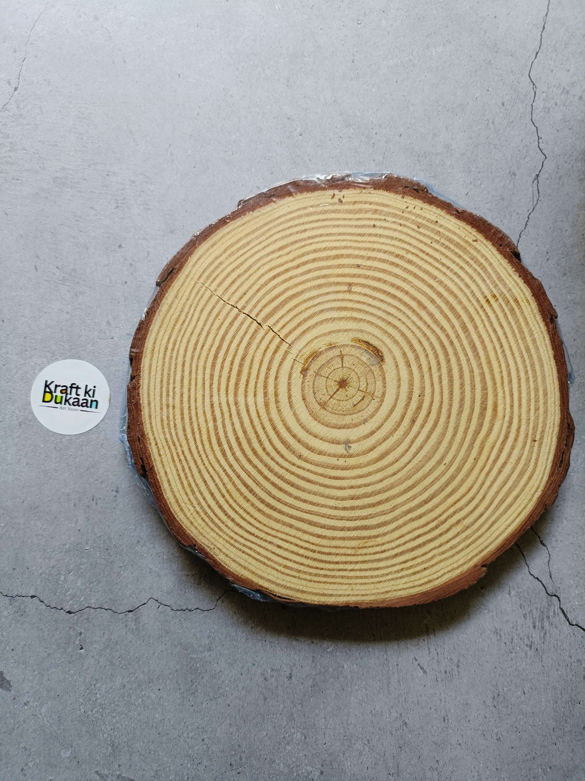 Round wooden slice with concentric growth rings, 20–22 cm diameter.