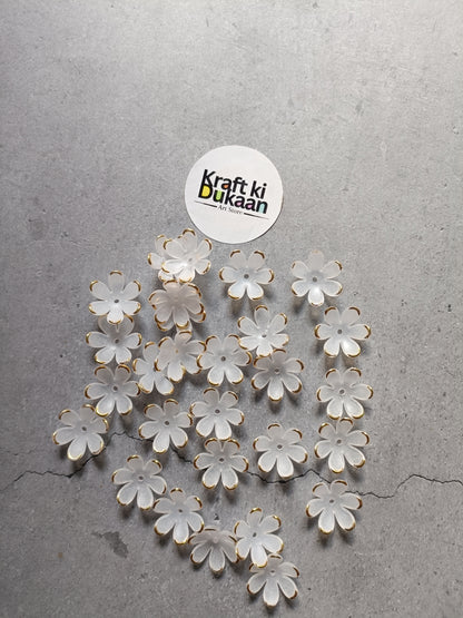 White flower-shaped beads scattered on surface, with gold-tone metal loops
