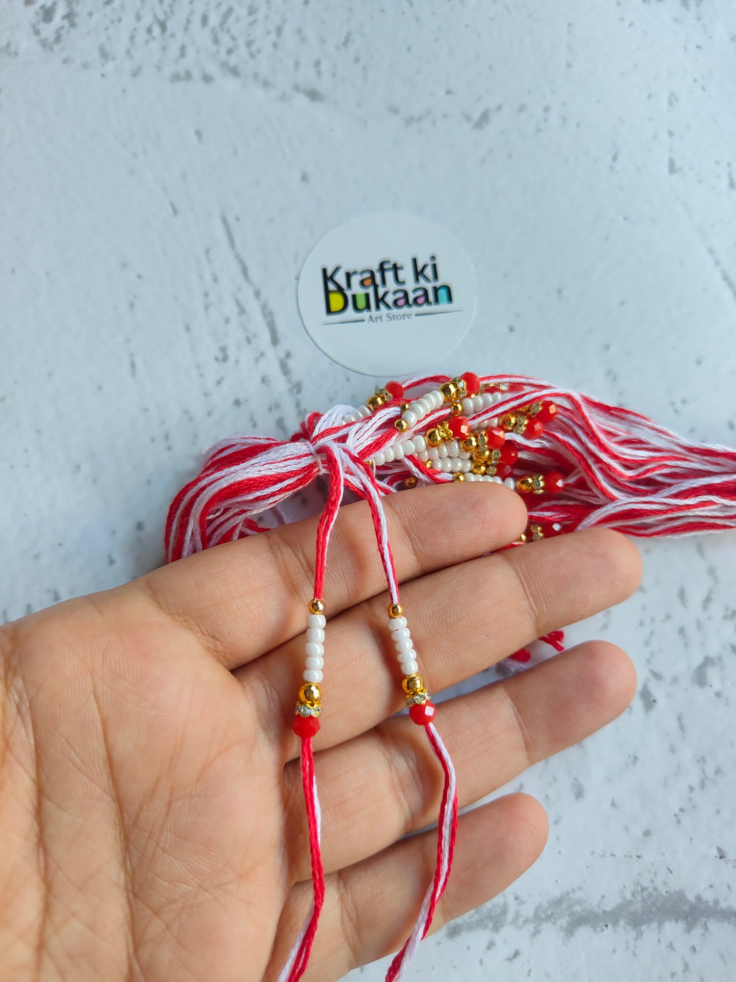 Red rakhi dori set with pearl-like beads and small charm details