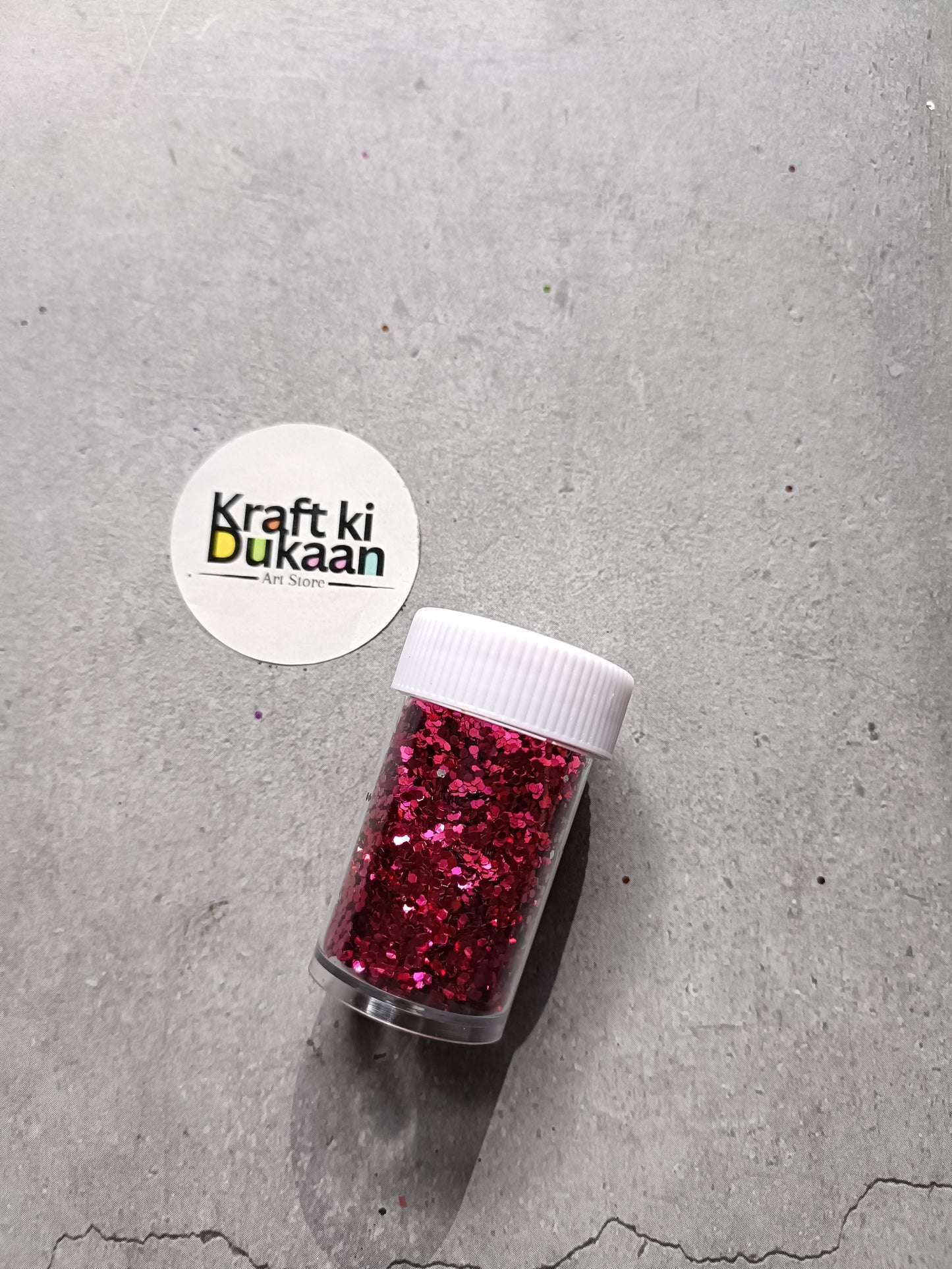 Hexagon-shaped glitter jar with ruby red glitter flakes and white screw lid