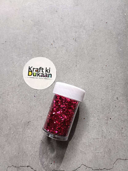 Hexagon-shaped glitter jar with ruby red glitter flakes and white screw lid