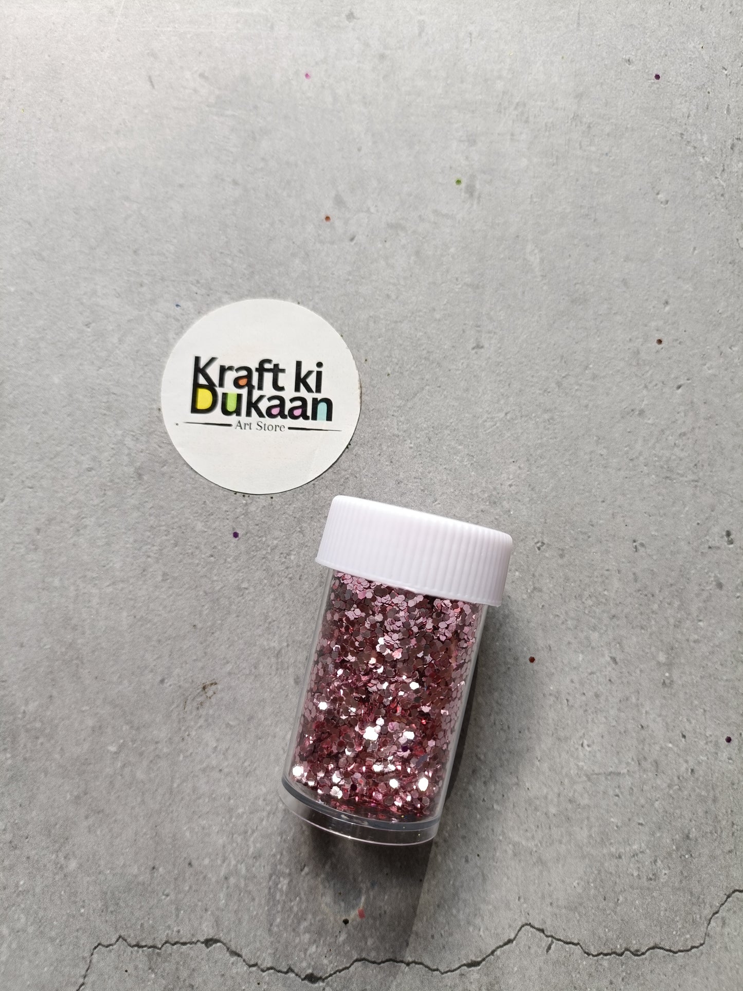 Hexagon glitter jar with rose-pink glitter in a small white-lidded bottle