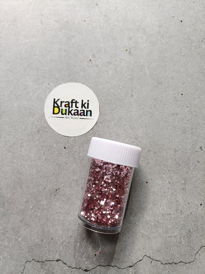 Hexagon glitter jar with rose-pink glitter in a small white-lidded bottle